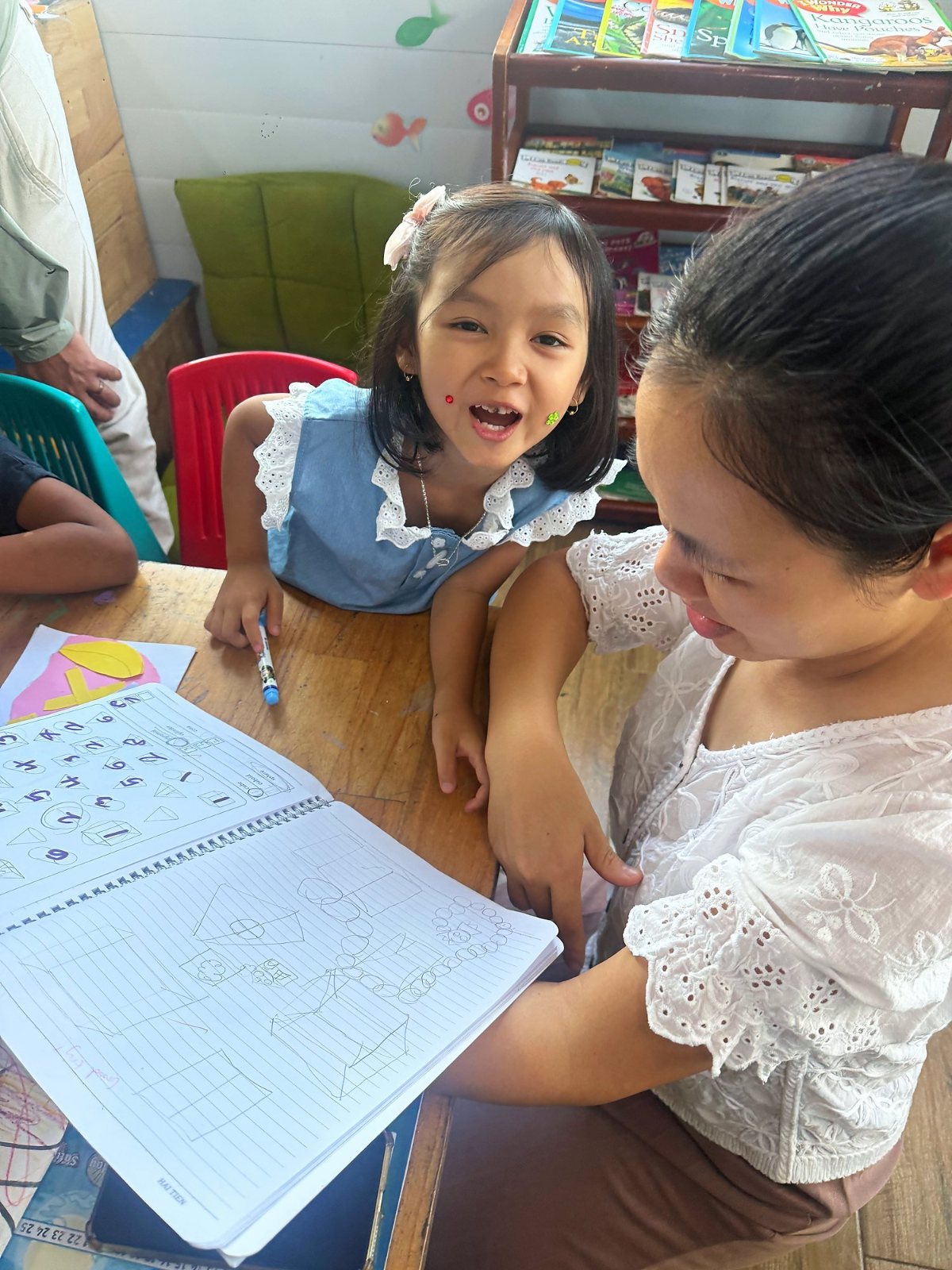 A Year 1 student showing a parent the shapes in her maths book