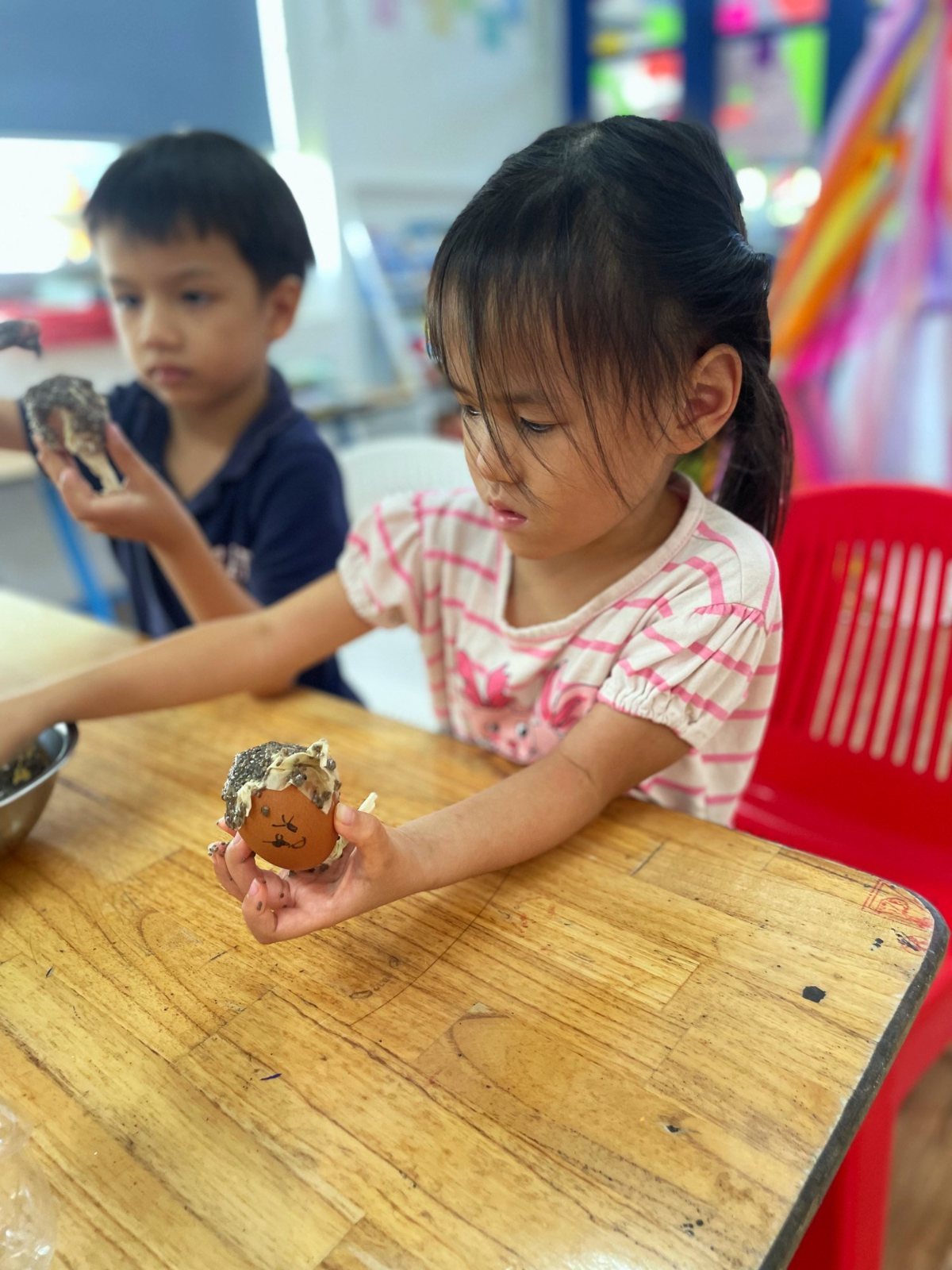 Kindergarten children holding up the eggshells they filled with soil for chia seeds