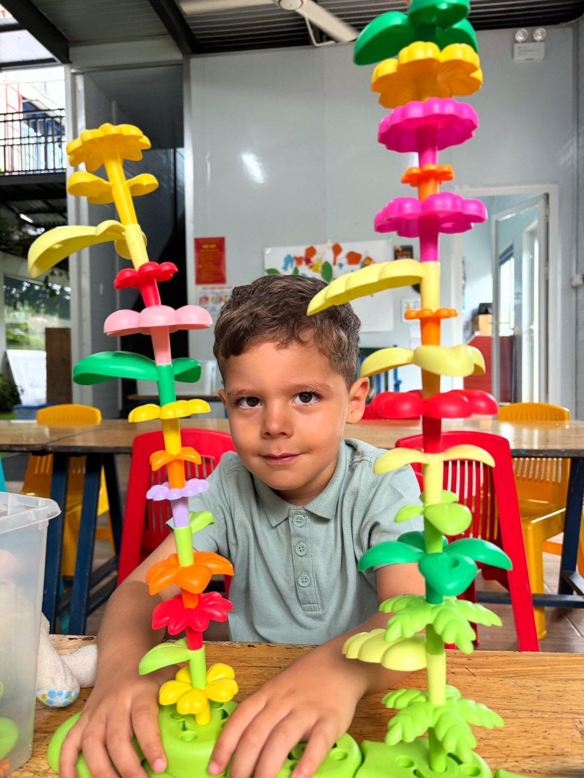 A Nursery boy sitting between two tall flower towers he built