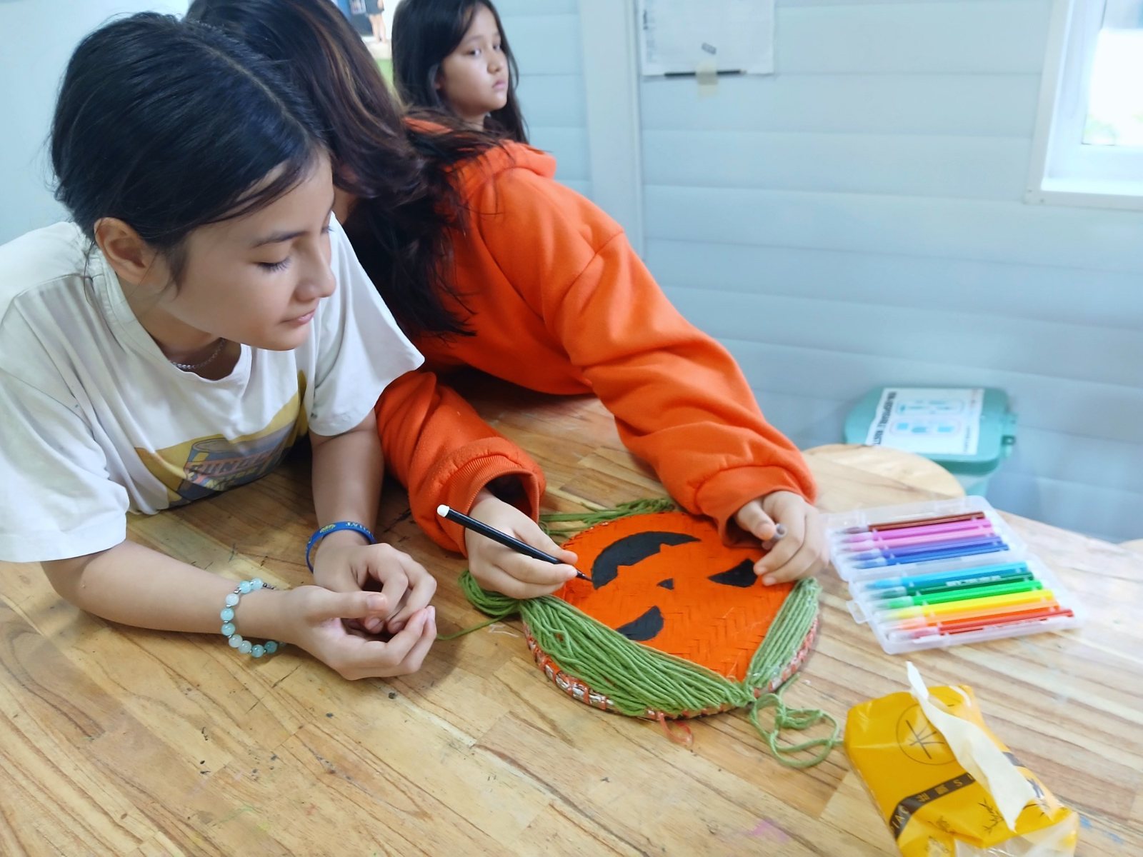 Year 7 students drawing a face on the woven pumpkin they made