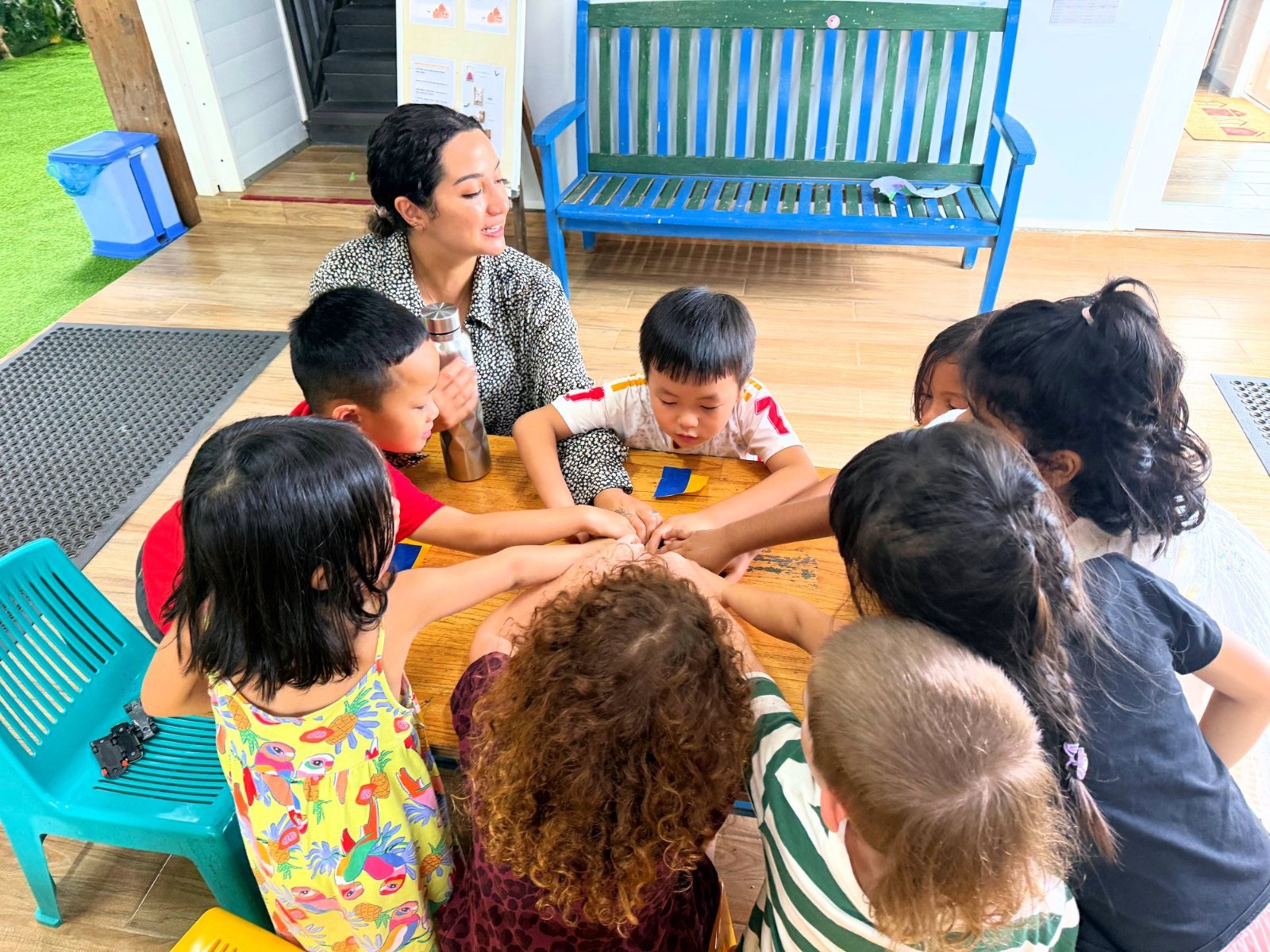 Year 1 children meeting hands in the middle of the table with their teacher