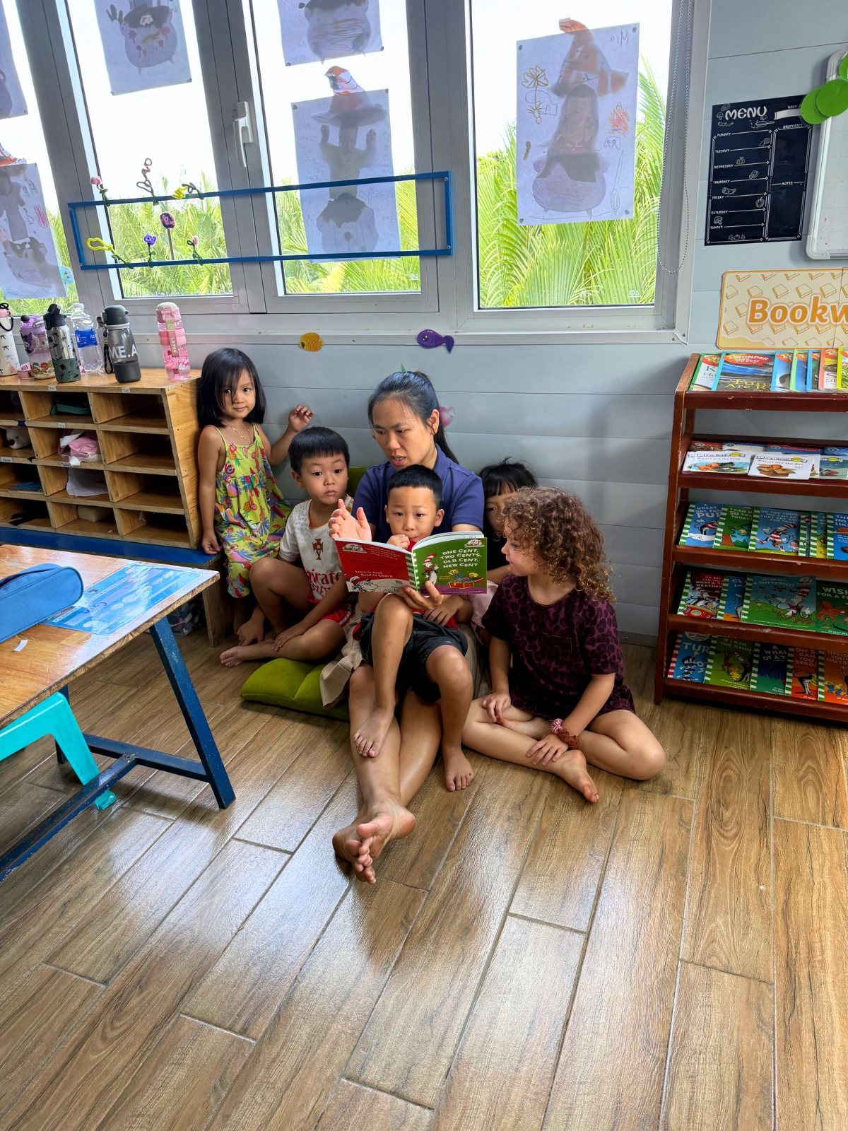 A teacher reading a picture book with Year 1 children in the book corner
