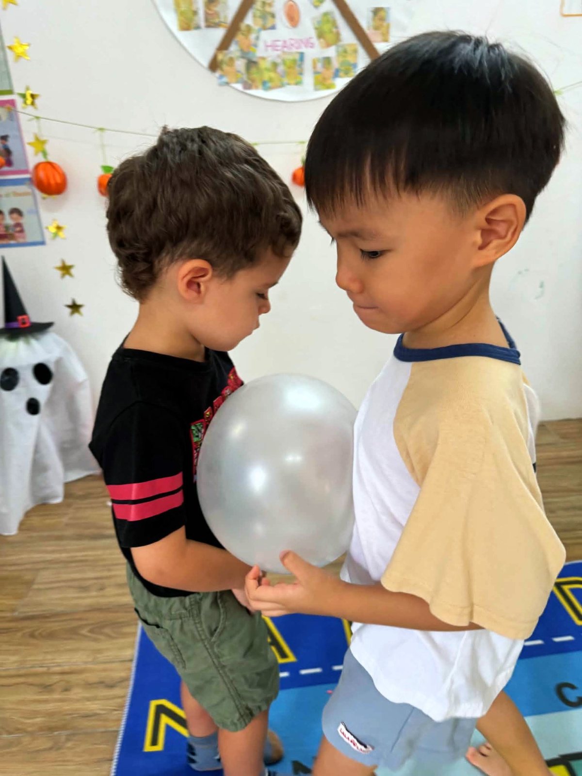 Two Kindergarten children carrying a balloon between them without using their hands