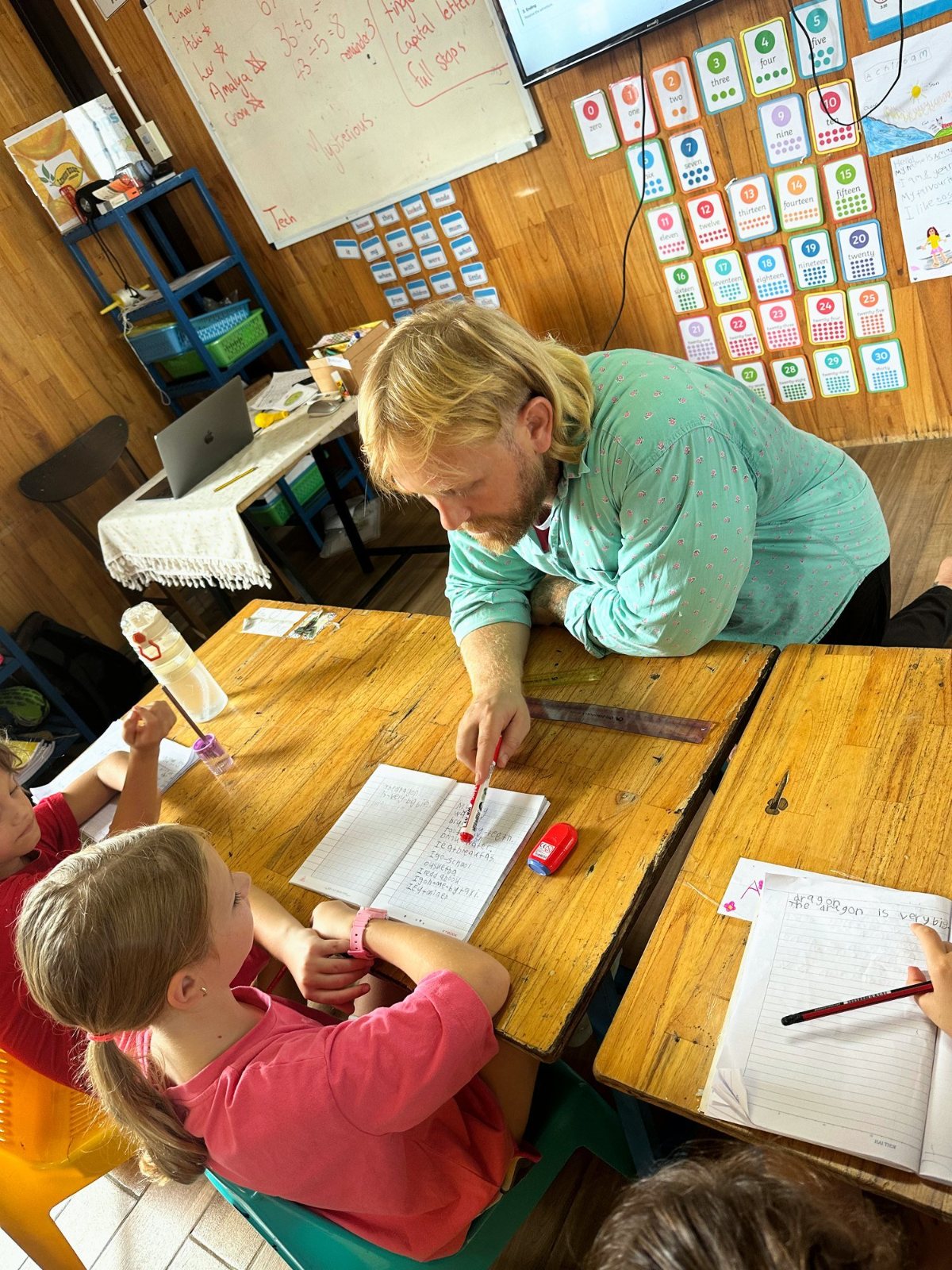 A Year 2-3 teacher helping a child with her sentences about a dragon