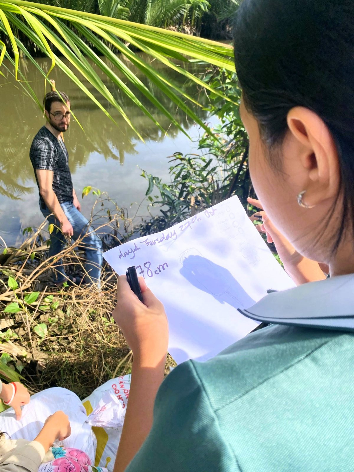 A Year 7 student writing down the river's water level beside the riverbank