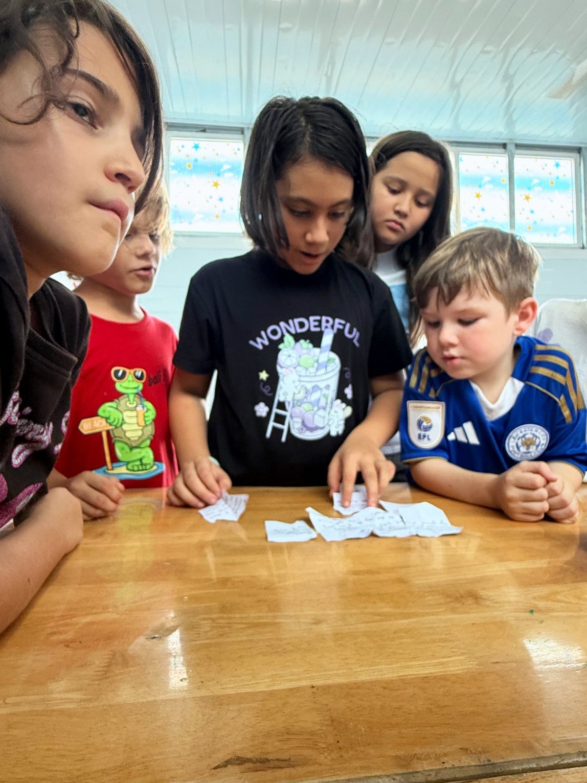 Younger students fitting torn clue notes together at the Year 7 mystery