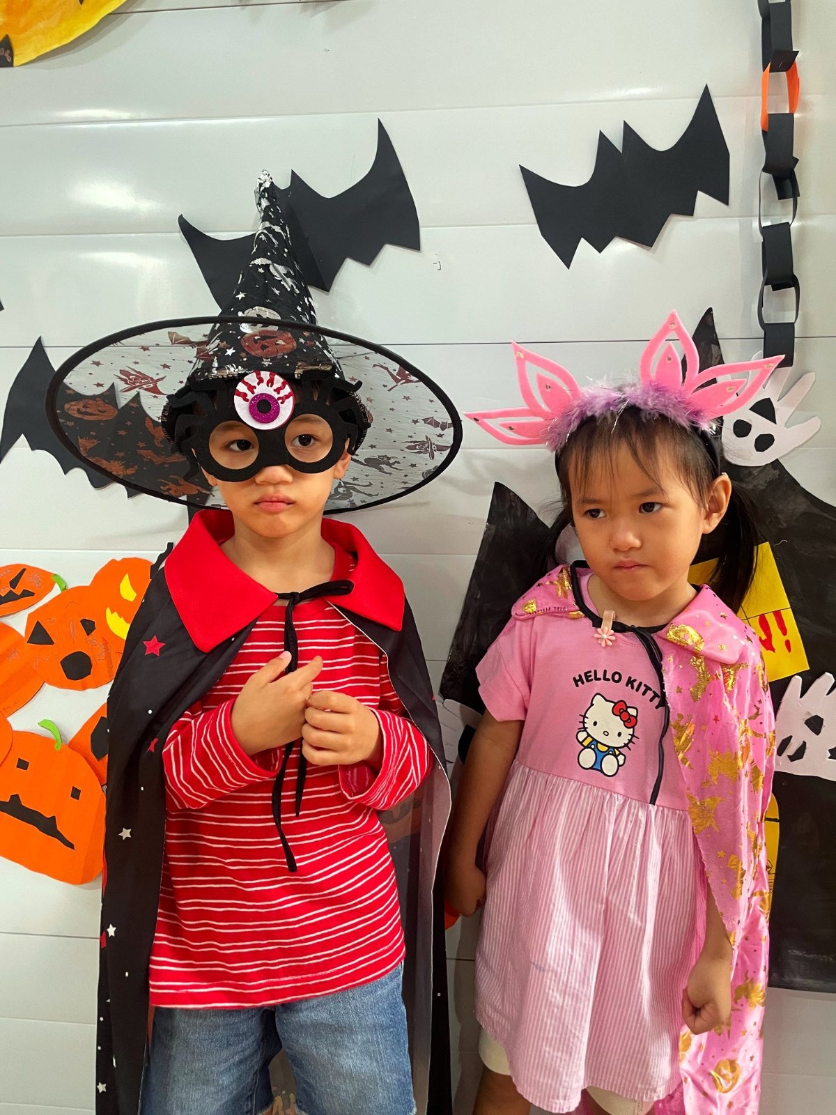 Two Kindergarten children in a witch hat and bunny ears at the Halloween wall