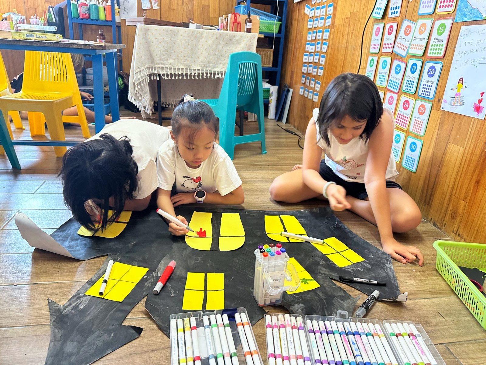 Year 2-3 children drawing in the windows of a paper haunted house